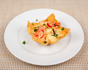 Snack with tomato baked in the dough with cheese on a white plate.