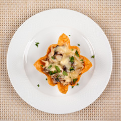 Snack with mushrooms baked in the dough with cheese on a white plate.