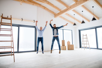 A mature man jumping with his senior father in new house, a new home concept.