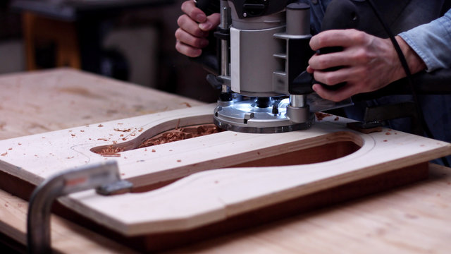 Luthier makes a hole in a piece of wood for guitar