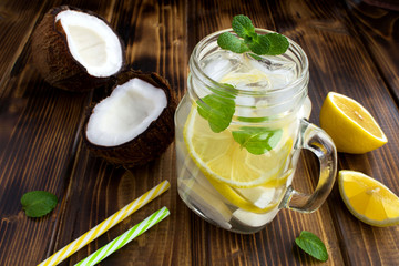 Cold lemonade with coconut,lemon and mint on the  brown wooden background