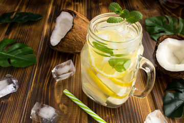 Cold lemonade with coconut,lemon and mint on the  brown wooden background