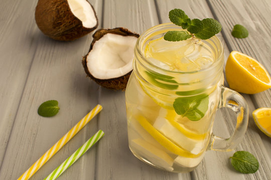 Cold lemonade with coconut,lemon and mint on the grey wooden background