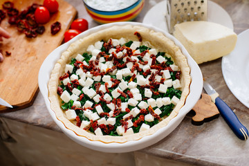 The process of making French quiche. Ingredients pie quiche. French quiche with cheese, spinach, mushrooms, bacon, dried tomatoes. Cooking.