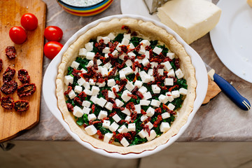 The process of making French quiche. Ingredients pie quiche. French quiche with cheese, spinach, mushrooms, bacon, dried tomatoes. Cooking.