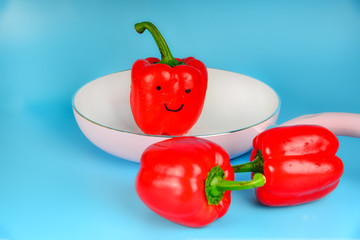 Red pepper lies on a white pan on a blue background