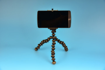 Tripod for smartphone on a blue background, tripod for the photographer
