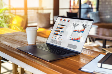 Close up of laptop with graphs, charts on screen,cup of coffee on table in empty room, cafe....