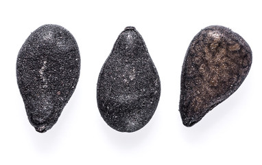 Three black sesame seeds isolated on white background. Macro shot.