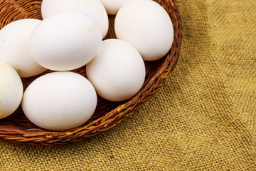 White chicken eggs in wicker basket on sackcloth background