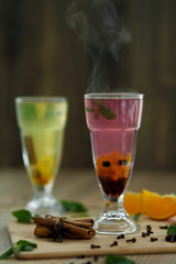 two glasses with colored hot drinks from which steam comes. winter hot seasonal drinks