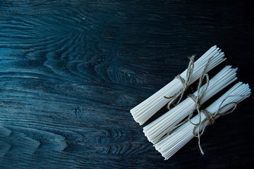 Raw udon noodles in rolls on a dark wooden background. Place for text. View from above.