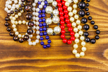 Different beads necklaces on wooden background