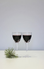 Gentle composition - two glasses of red wine on the table and a pine branch