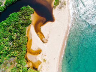 Aerial top of river tropical merging to white sand beach and turquoise clear sea water with small...