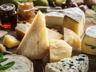 Piece of Parmesan cheese and assortment of different cheeses at the background.