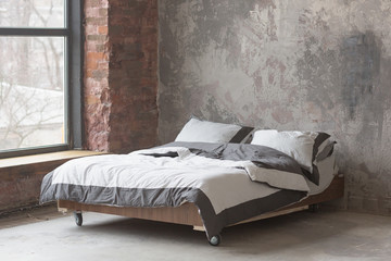 Loft style bedroom interior with bed, gray design, brick texture and concrete wall