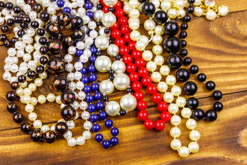 Different beads necklaces on wooden background