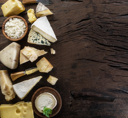 Assortment of different cheese types on old wooden background. Top view.
