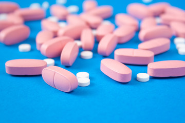Obraz na płótnie Canvas White and pink pills on blue background. Medicine and healthcare concept