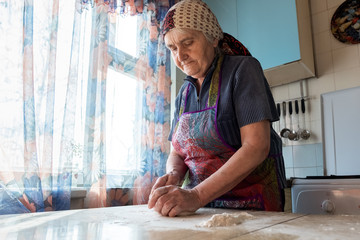 Grandmother cooking in the kitchen, kneading dough for bakery 