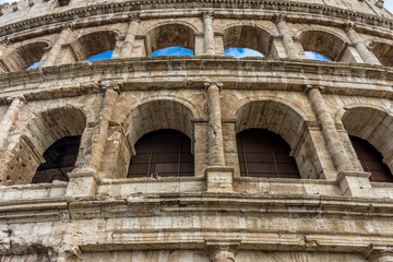 Obraz premium Facade of the Great Roman Colosseum (Coliseum, Colosseo), also known as the Flavian Amphitheatre. Famous world landmark. Scenic urban landscape.