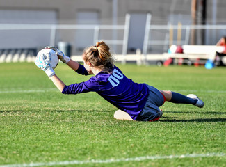 Girl playing with soccer ball in a green grassy field
