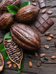 Cocoa pod, cocoa beans and chocolate on the wooden table. Top view.