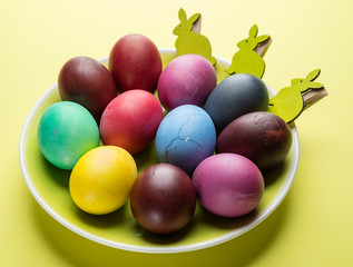 Colorful Easter eggs as an attribute of Easter celebration on the yellow plate.