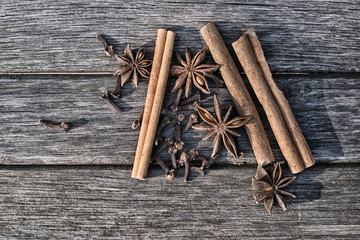 Three sticks of cinnamon, four star fruit of star anise and cloves on old boards - 252916102