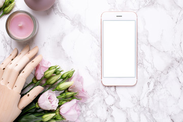 Mobile phone mock up and wooden hand with pink flowers on marble background