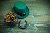 Happy St Patricks Day leprechaun hat with gold coins and lucky charms on vintage style green wood background. Top view