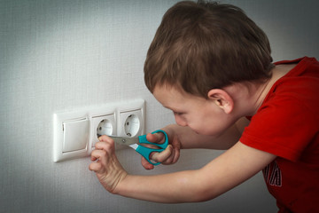 Child puts the scissors in the socket