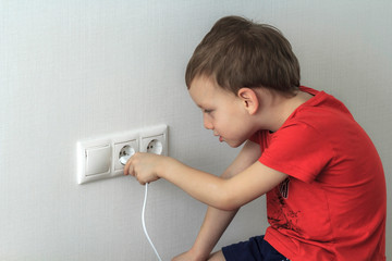 Child playing with electrical socket. Concept of danger to children