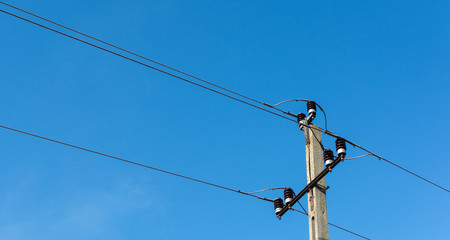 Concrete Electric Pylon or Post with Electric Wires Against Clear Blue Sky.