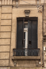 Fototapeta na wymiar Old window with iron shutters and a balcony with bars