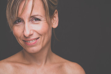 Portrait of a smiling middle aged caucasian woman against dark background - radiating confidence...