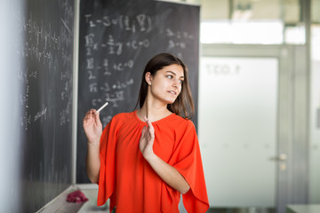 Pretty, young college student writing on the chalkboard/blackboard during a math class