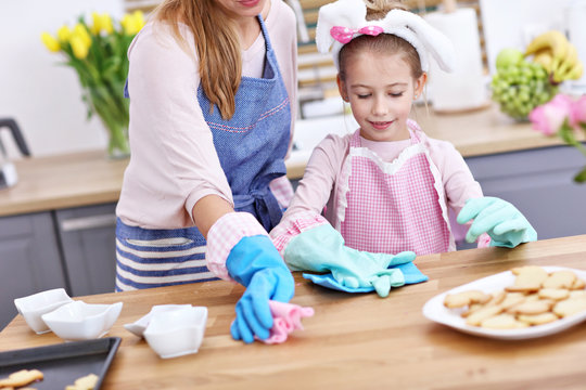 Little girl and her mom in aprons having fun in the kitchen