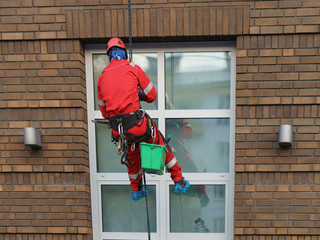 Industrial Alpinism. Workers wash the windows of houses in the street