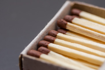Match in box, carton background. Macro photography. Close-up shot. A lot of matches lying in a matchbox on a black background