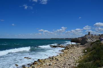 Fototapeta na wymiar The Black Sea rolls in waves with foam on a rocky shore