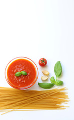 pasta secca integrale ed ingredienti per cucinarla, salsa fresca di pomodoro, aglio, basilico, peperoncino sullo sfondo bianco