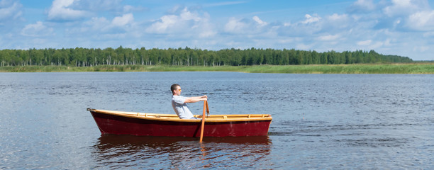 a man on a boat floats down the river to the forest