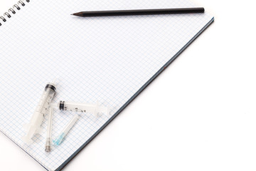 Needles for medical injections are on the notebook isolated on white background.