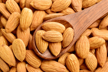 almonds, almonds on wooden spoon over almonds background, top view