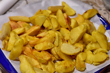 fried potatoes wedges on a plate macro