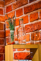 Show-window in shop of cosmetics on the background of a red bricks. On a wooden support glass bottles and violet flowers and herbs