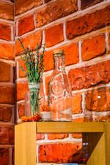 Show-window in shop of cosmetics on the background of a red bricks. On a wooden support glass bottles and violet flowers and herbs