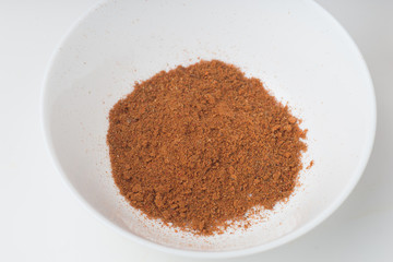 Chili powder in white bowl on white background